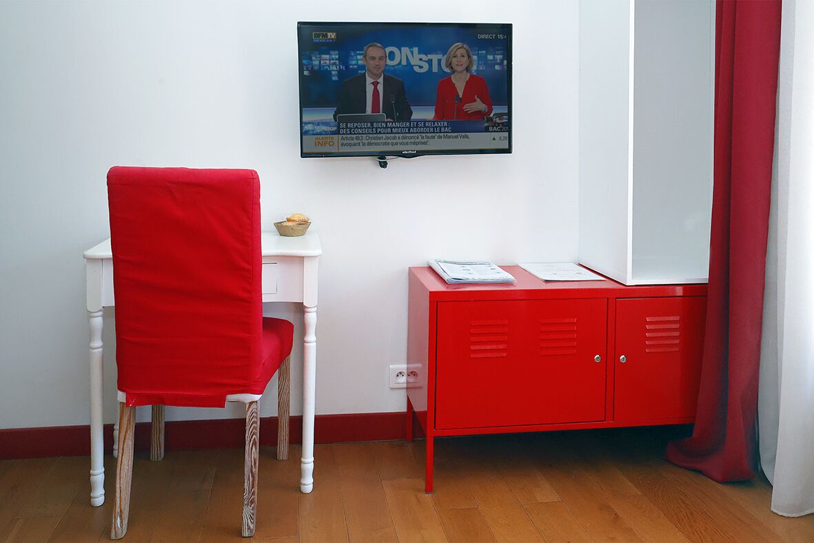A room with a red chair, a small white table, and a red cabinet.