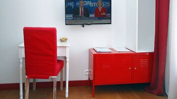 A room with a red chair, a small white table, and a red cabinet.