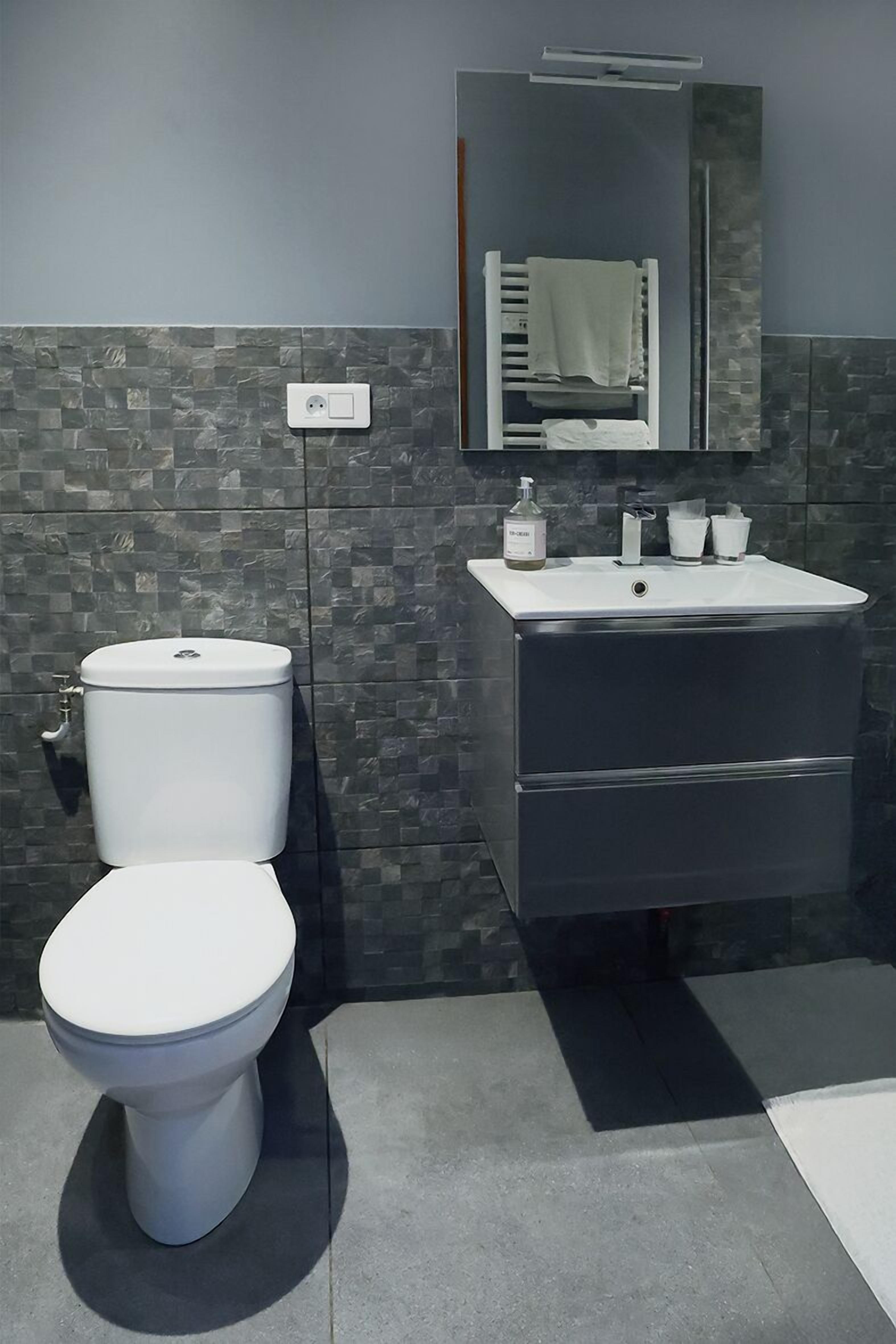A modern bathroom with a toilet, sink, and mirror.