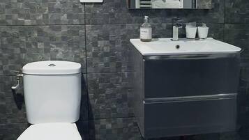 A modern bathroom with a toilet, sink, and mirror.