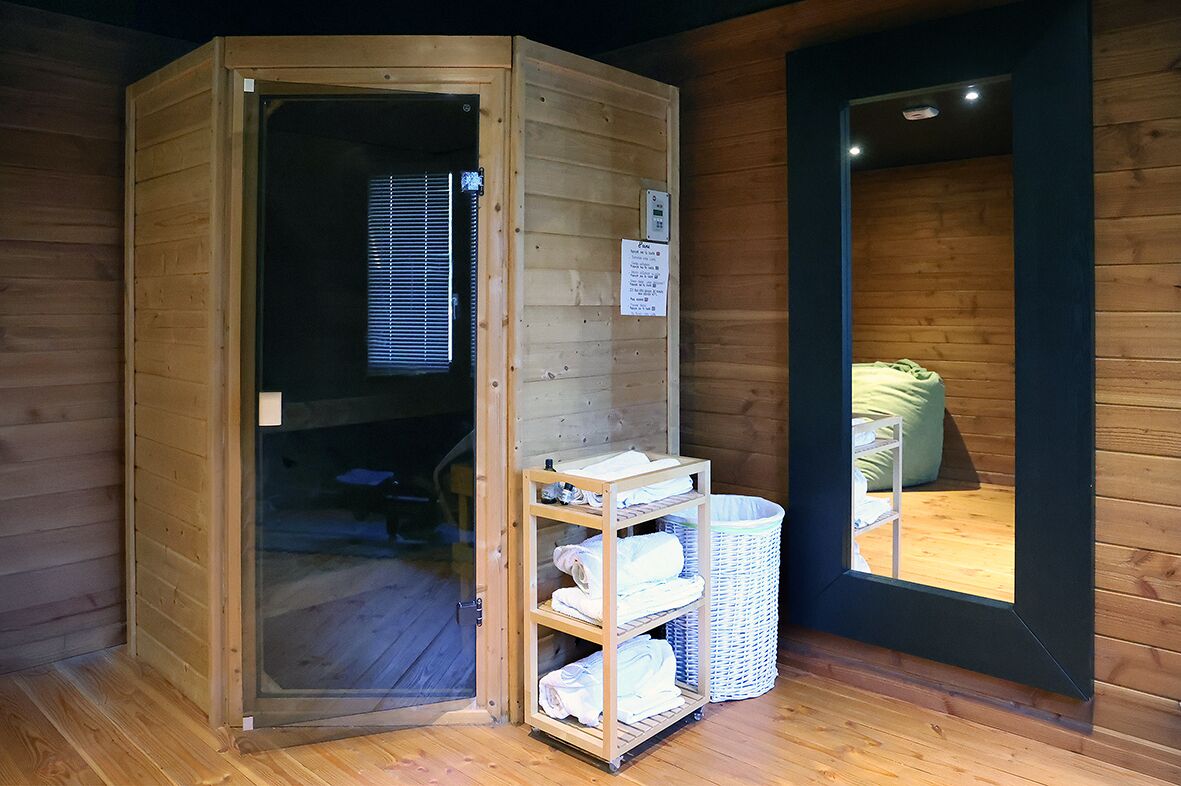 Un sauna con puerta de madera, un estante con toallas y una cesta de mimbre.