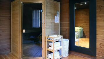 Un sauna con puerta de madera, un estante con toallas y una cesta de mimbre.