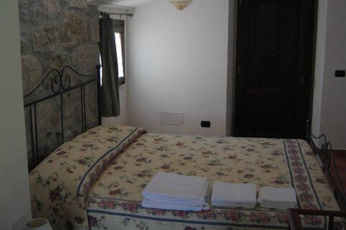 Ein Schlafzimmer mit Bett, Nachttisch, Fenster und Tür.