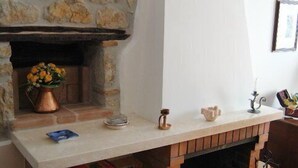 Une cheminée en pierre avec une étagère décorative, un vase à fleurs et un chandelier.