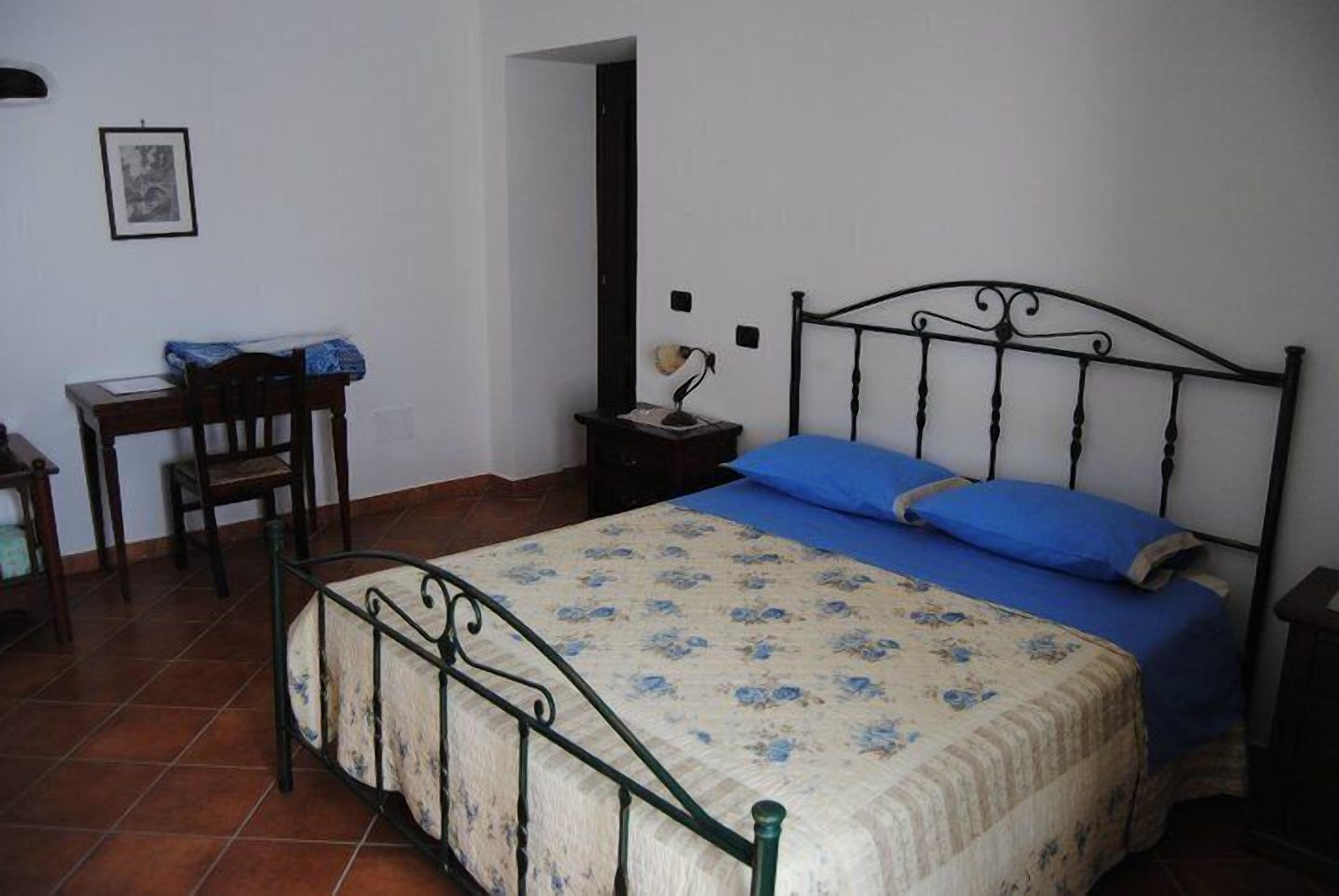 A bedroom with a bed, a desk, and a chair.