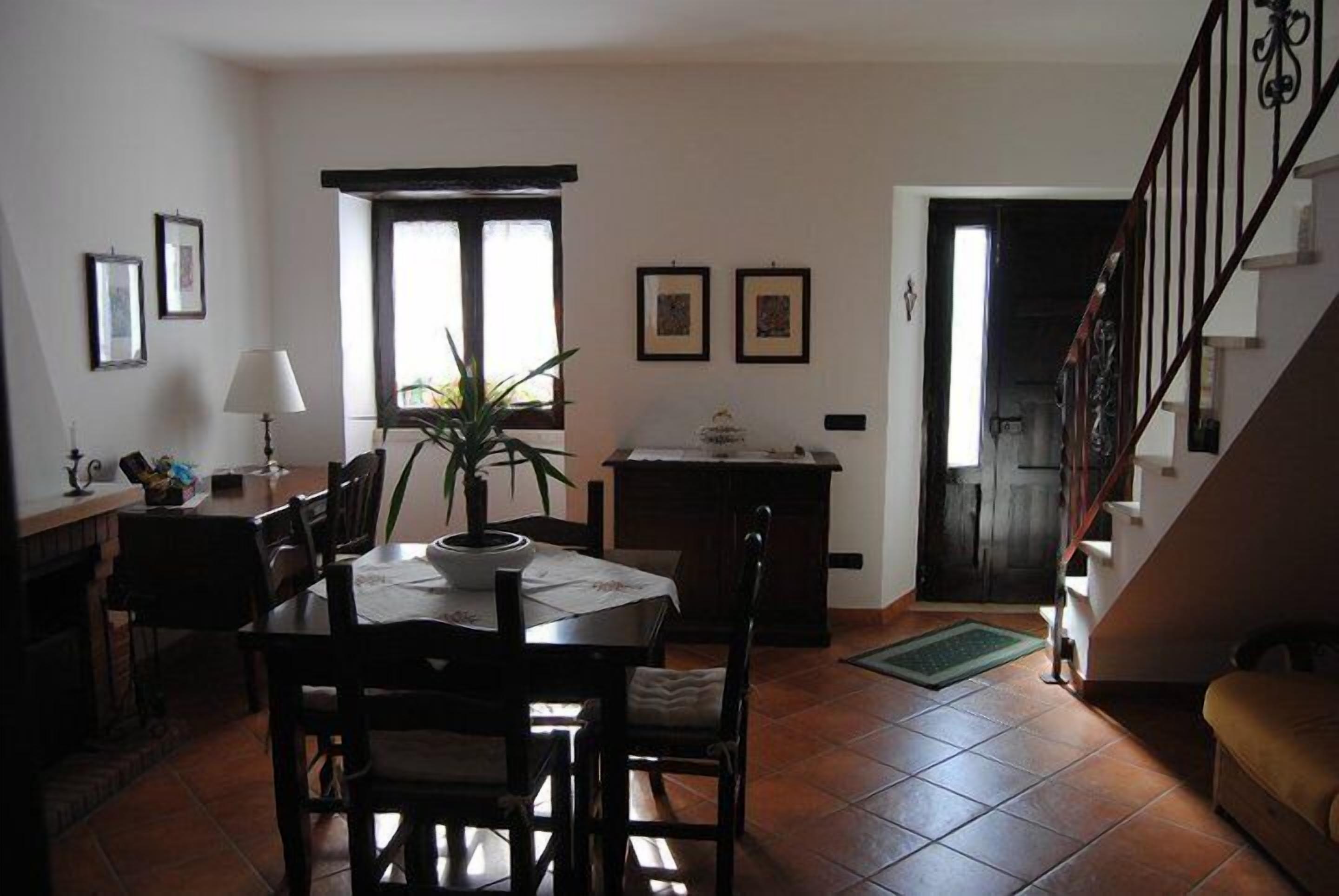 Un comedor con una mesa y sillas, una planta en maceta, una lámpara y cuadros en la pared.
