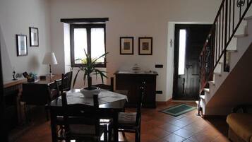 Un comedor con una mesa y sillas, una planta en maceta, una lámpara y cuadros en la pared.