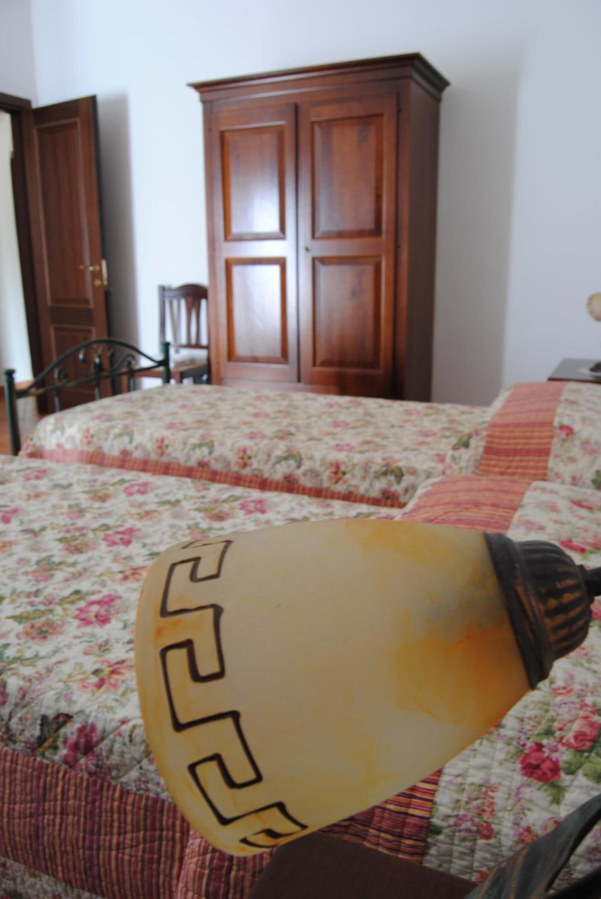 Un dormitorio con cama, armario de madera y una silla.