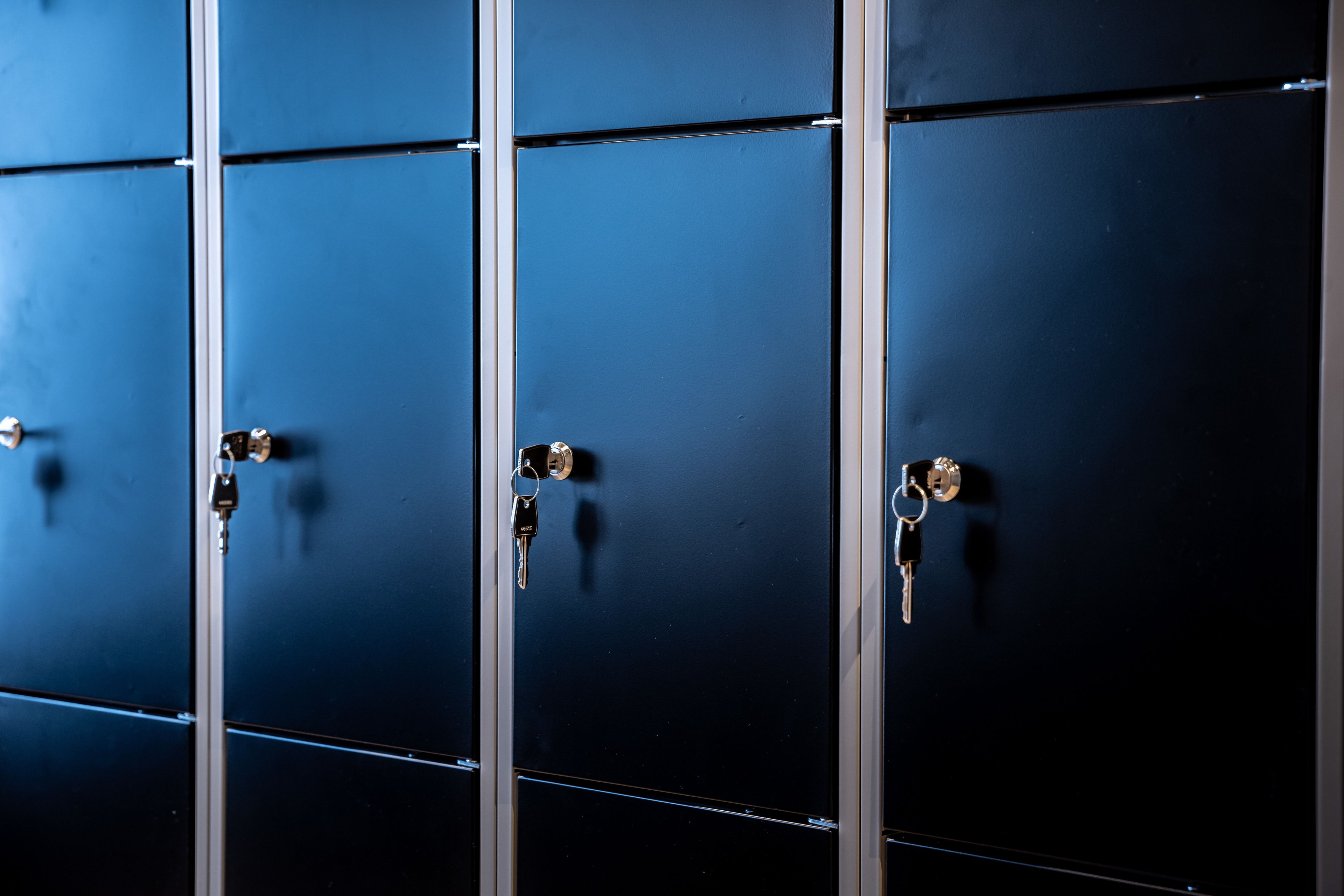 A row of blue lockers with metal handles and keys.