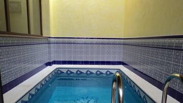 Una piscina cubierta, sombrillas, tumbonas