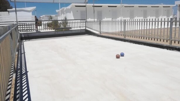 A rooftop with a white fence, a basketball court, and a clear blue sky. - Hotel Naica (Rimini)