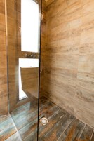 Um banheiro moderno com box de vidro, piso de madeira e pia com espelho acima.