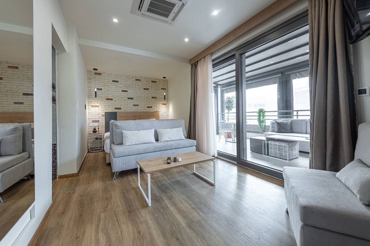A modern living room with a sofa, a coffee table, and a view of the outdoors through large windows.