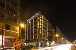 A multi-story hotel with illuminated signage, a ground-level restaurant, and a street view with cars.