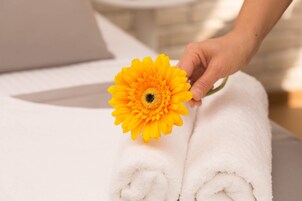 Una mano che tiene un fiore giallo sopra un asciugamano bianco.