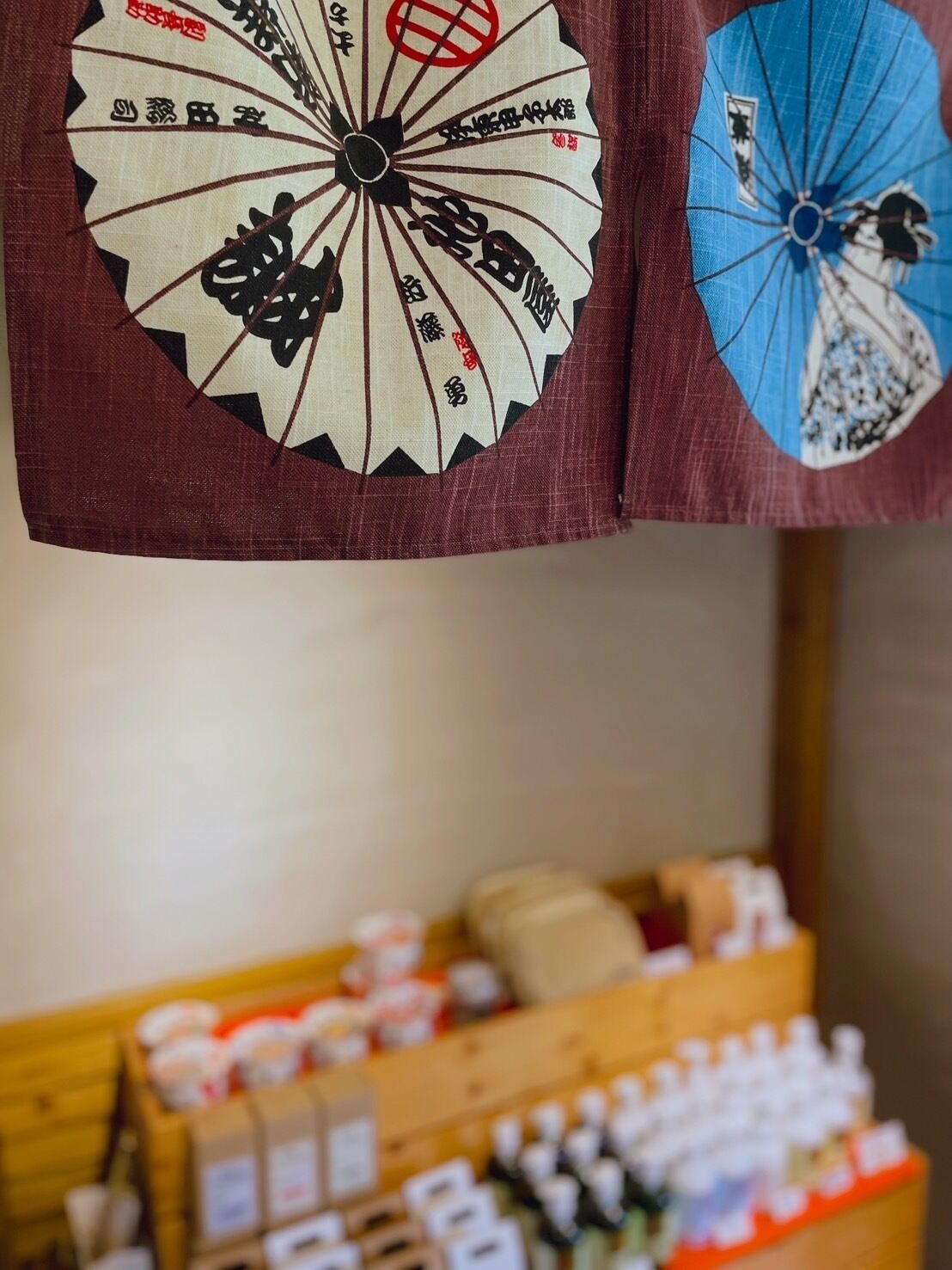 A traditional Japanese fan with calligraphy, a wooden display case with various items, and a blurred background.