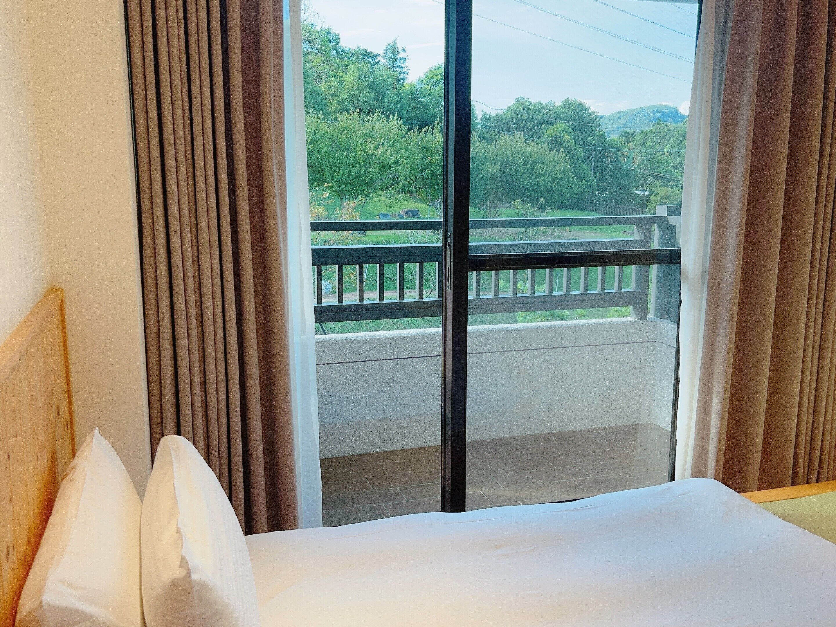 Une chambre d’hôtel dotée d’une grande fenêtre, d’un balcon et d’un lit avec du linge de lit blanc.