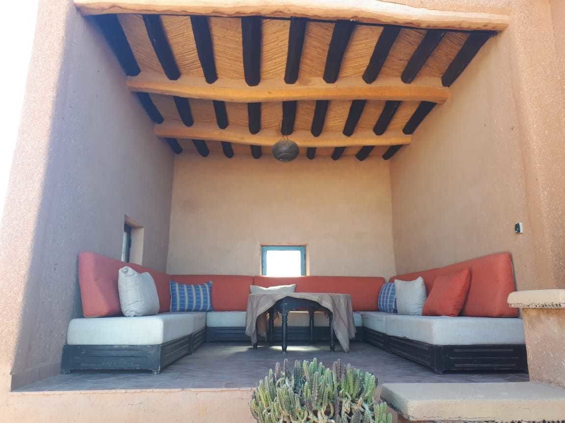 A cozy outdoor seating area with a wooden ceiling and a table.