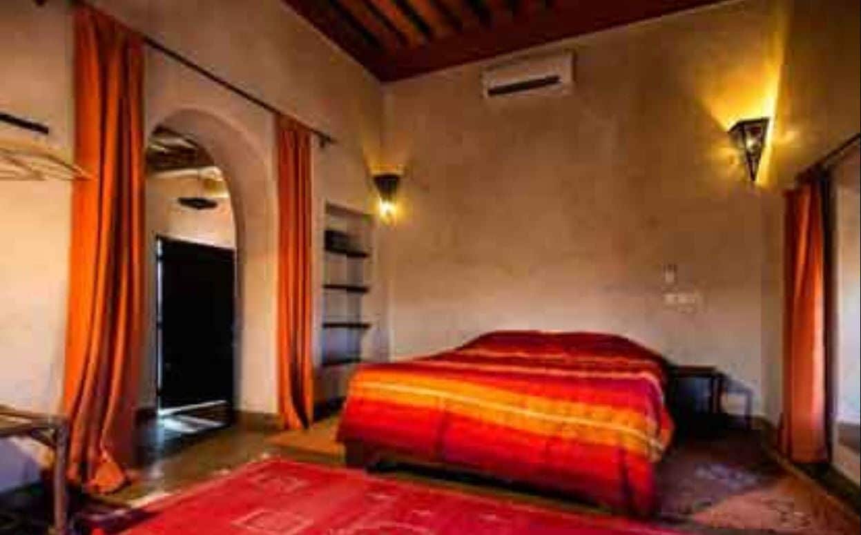 A hotel room with a bed, a nightstand, a lamp, and a window with curtains.