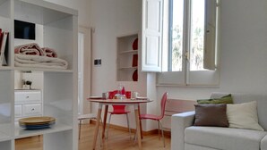 Un saló modern amb un sofà, una taula de dinar amb caires i una biblioteca.