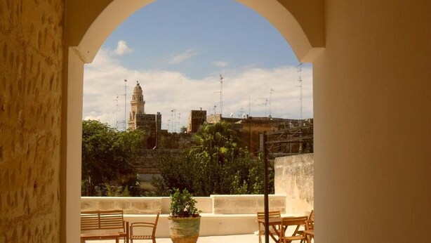 Un balcó amb vista a un edifici històric i vegetació circumdant.