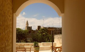 Un balcón con vistas a un edificio histórico y follaje circundante.