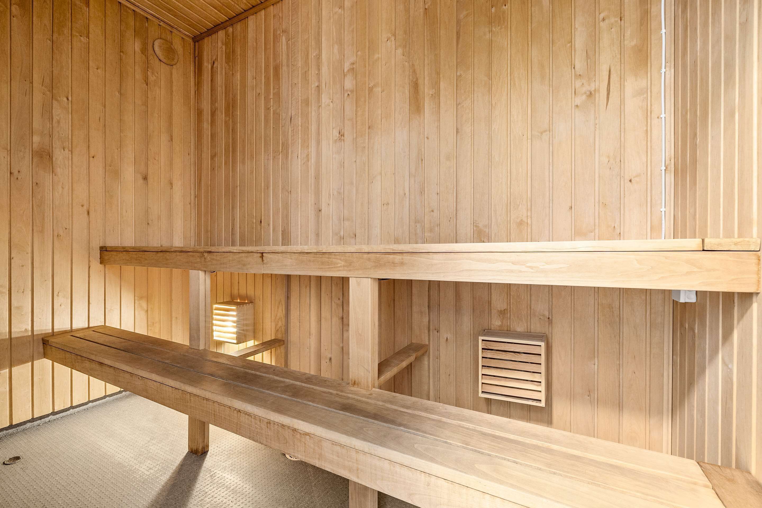A wooden sauna with benches and a ventilation system.
