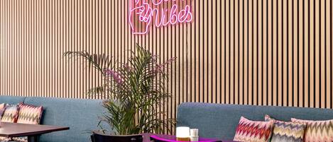 Ett modernt loungeområde med en neonskylt, en blå soffa och en vägg med träribbor.
