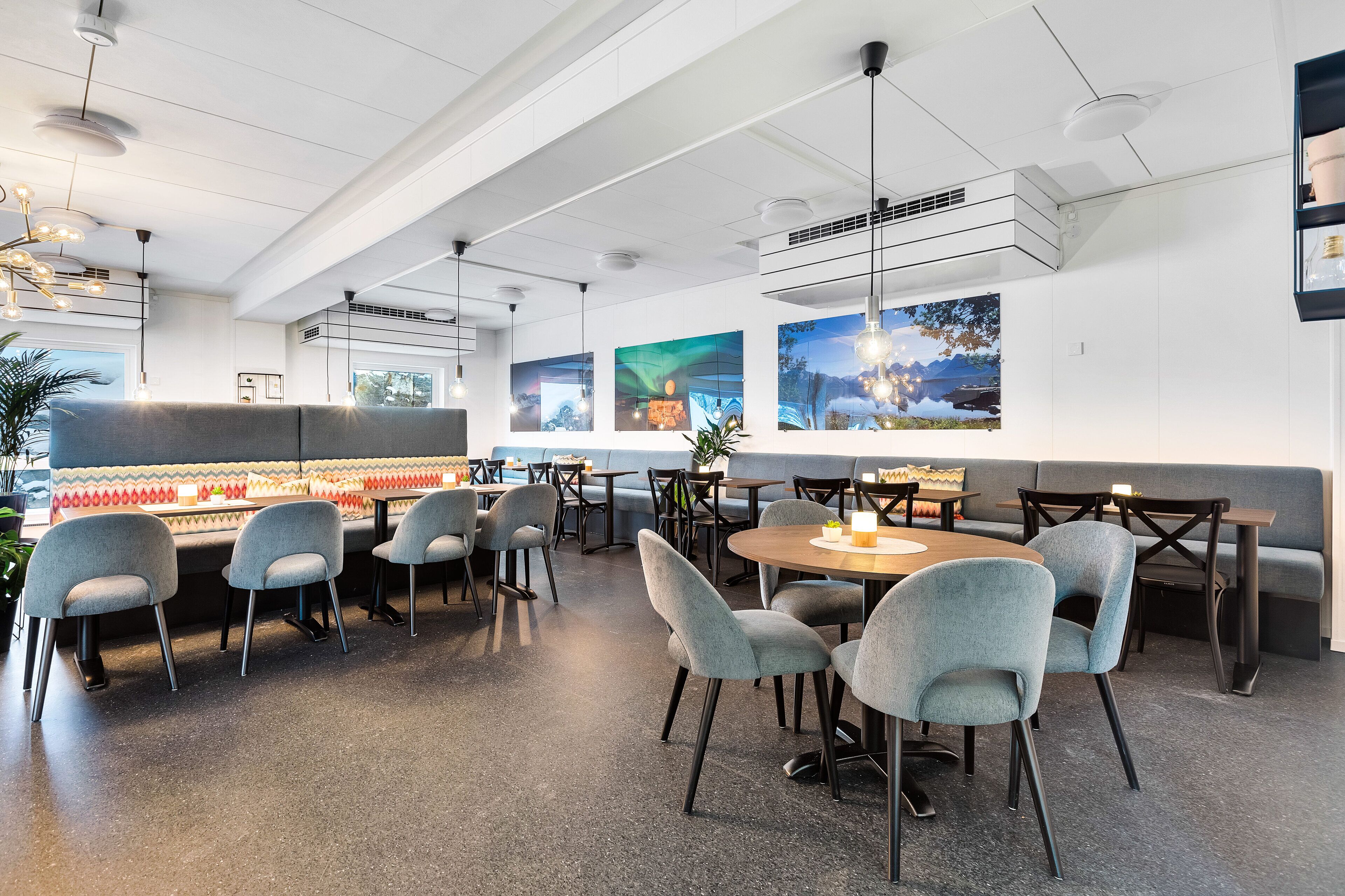 Un restaurante moderno con una barra larga, varias zonas de estar y obras de arte en las paredes.
