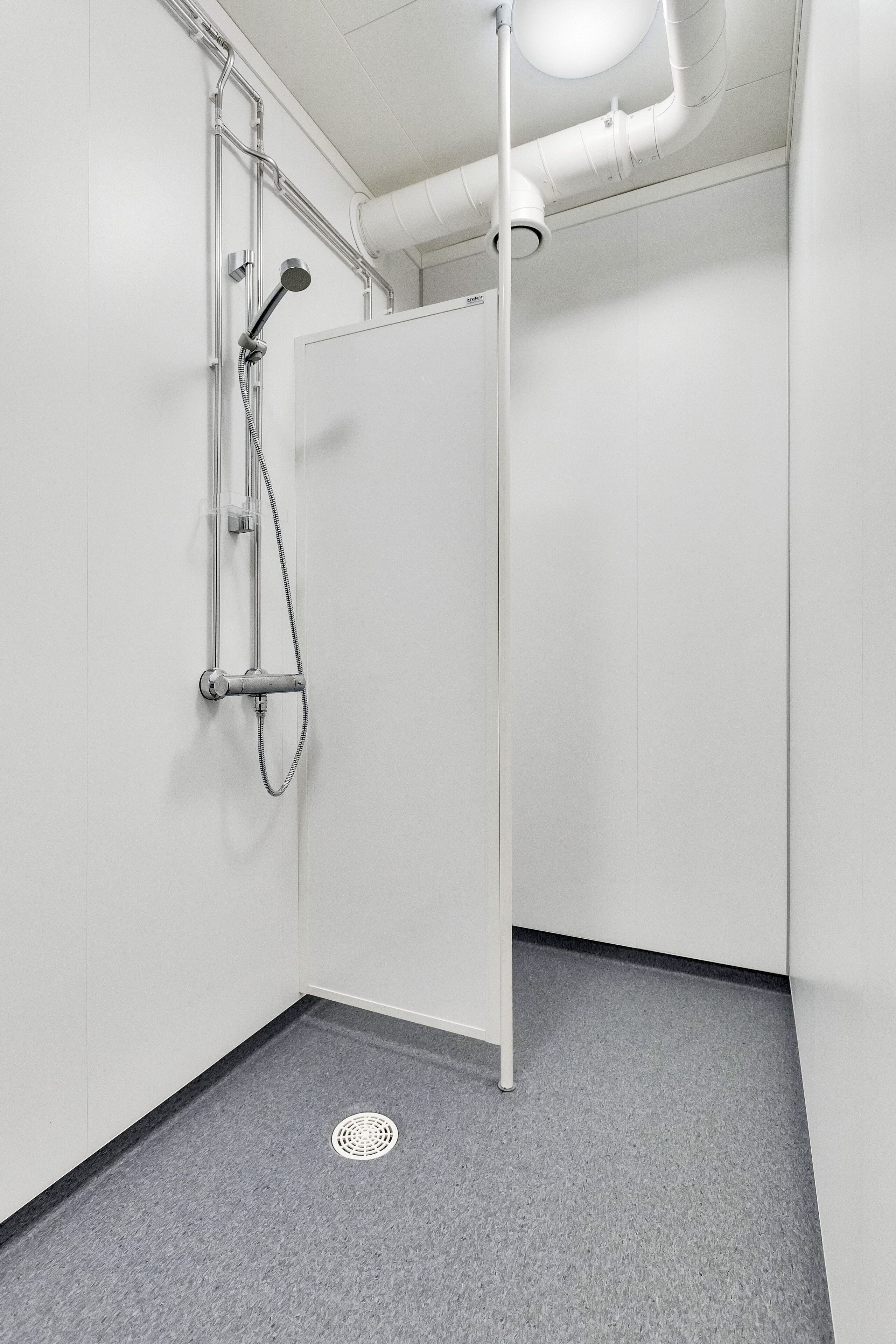 A modern shower with a handheld showerhead and a wall-mounted faucet.