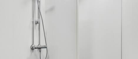 A modern shower with a handheld showerhead and a wall-mounted faucet.