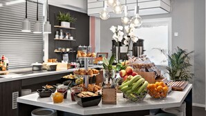 Un bufé de desayuno con diversas opciones de comida, como frutas, pasteles y bebidas.