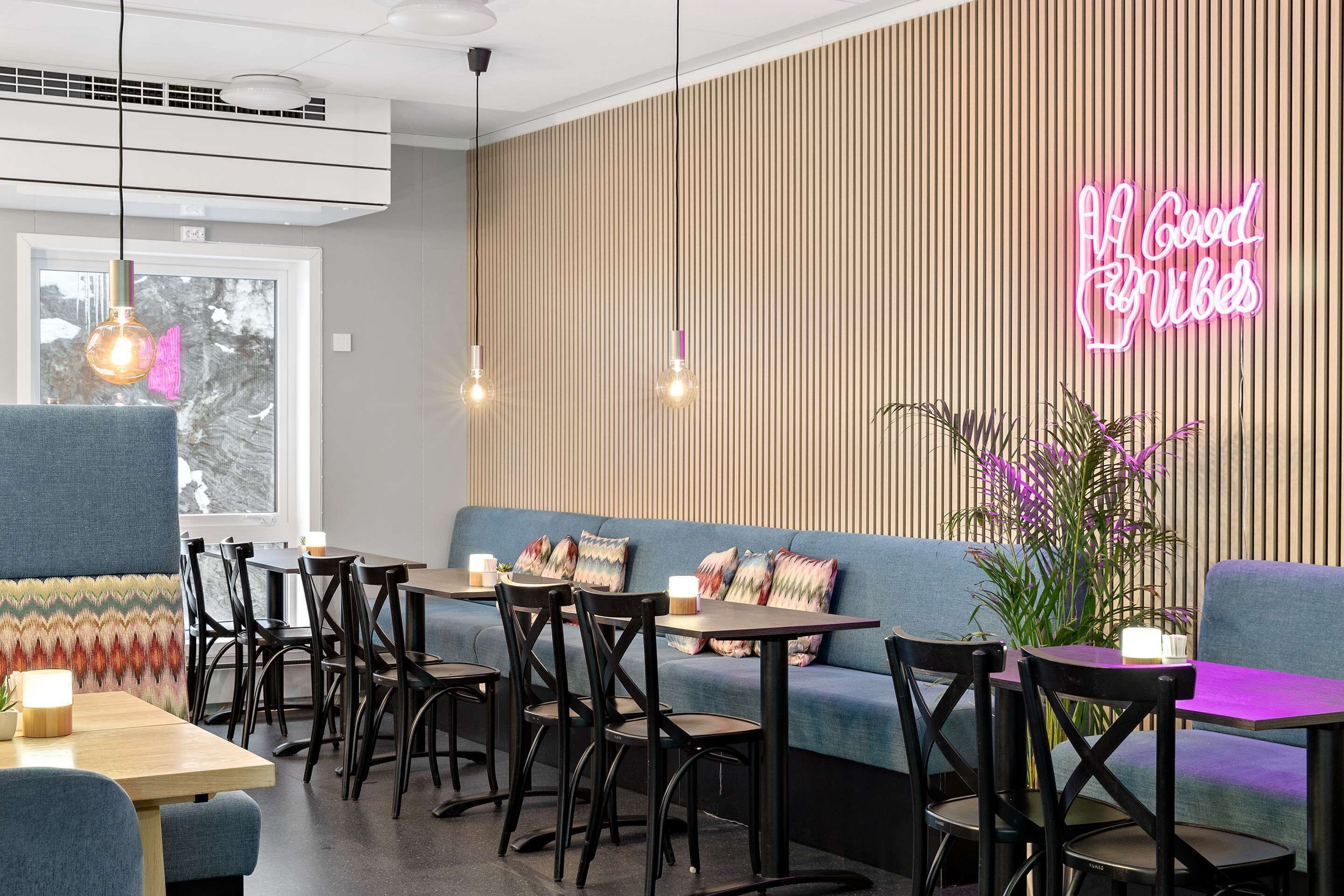 Un café moderno con un letrero de neón, listones de madera y una variedad de opciones de asientos.
