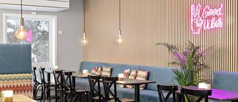 Un café moderno con un letrero de neón, listones de madera y una variedad de opciones de asientos.