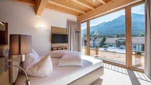 Une chambre moderne avec un grand lit, une télévision et une vue sur les montagnes.
