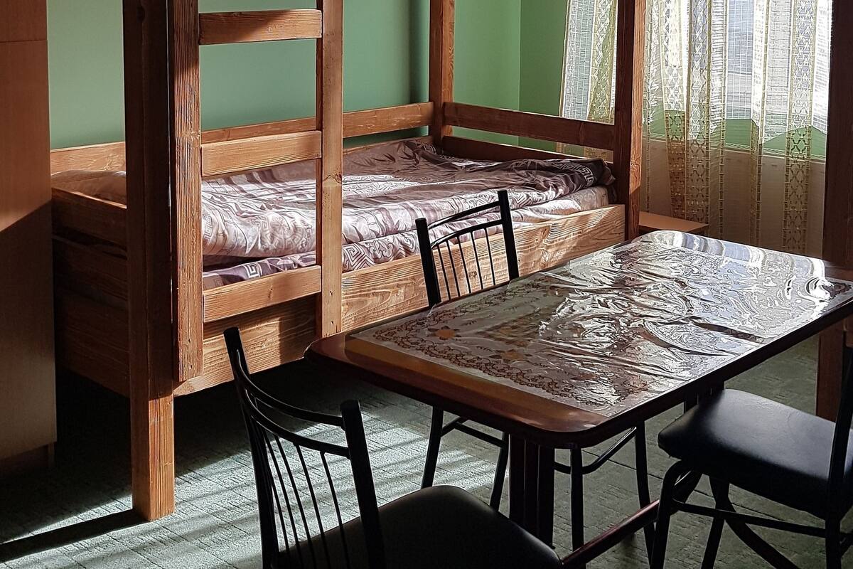 Dormitorio con literas, una mesa y sillas, paredes verdes y un candelabro.