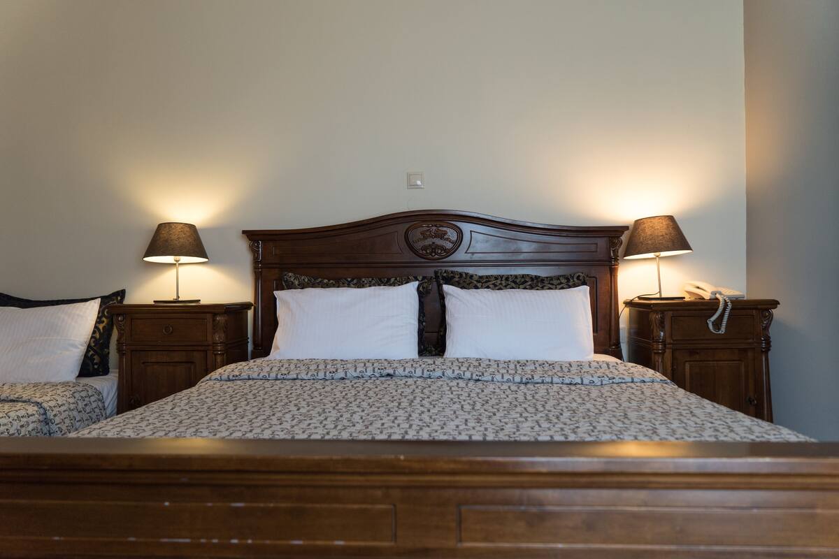 A double bed with a wooden headboard, two bedside tables with lamps, and a patterned bedspread.
