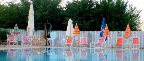 Una piscina con sillones de descanso y sombrillas.