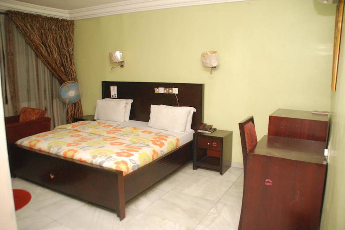 A bedroom with a bed, bedside tables, a desk, and a chair.