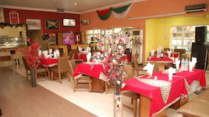 Un restaurante con varias mesas cubiertas con manteles rojos, sillas de madera y un centro decorativo.