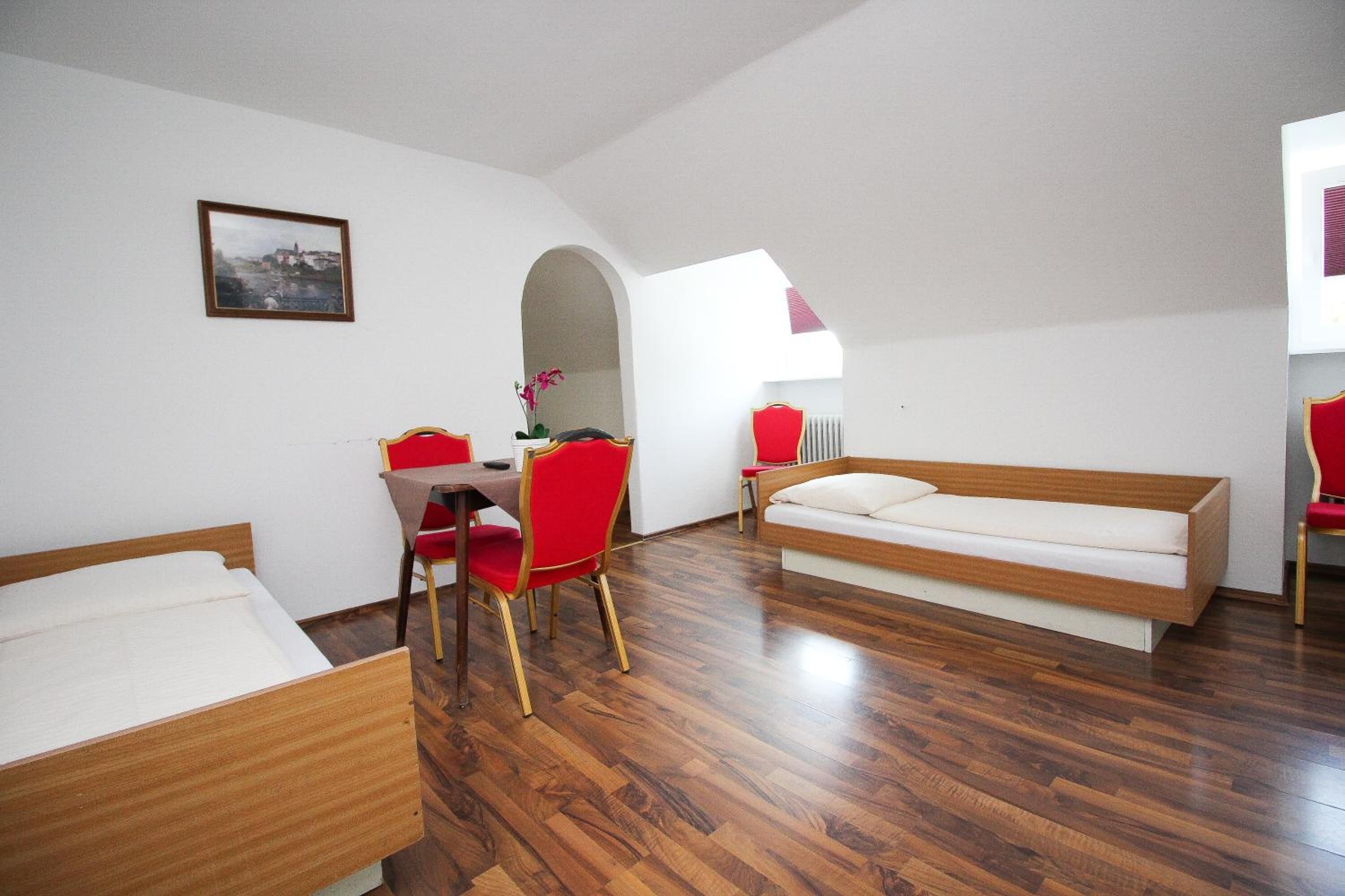 Una habitación con piso de madera, una cama, un escritorio con una silla y un sofá.