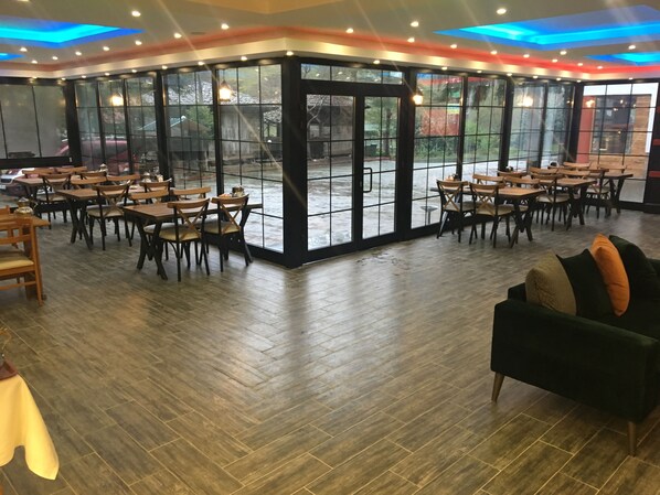 A spacious indoor dining area with wooden tables and chairs, large windows, and a modern ceiling design. - Sumela Holiday Hotel (Maçka)