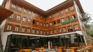 Um edifício de madeira com uma placa que diz "SUMELA HOLIDAY HOTEL".