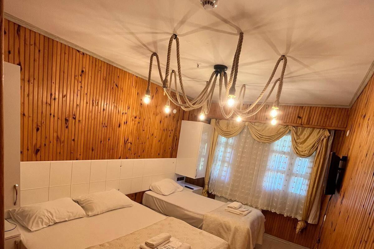 Habitación de hotel con dos camas, una pared de madera, una araña y un televisor.