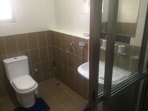 A small bathroom with a toilet, a sink, and a shower area.