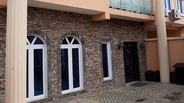 Un edificio de fachada de piedra, múltiples ventanas y un patio empedrado.