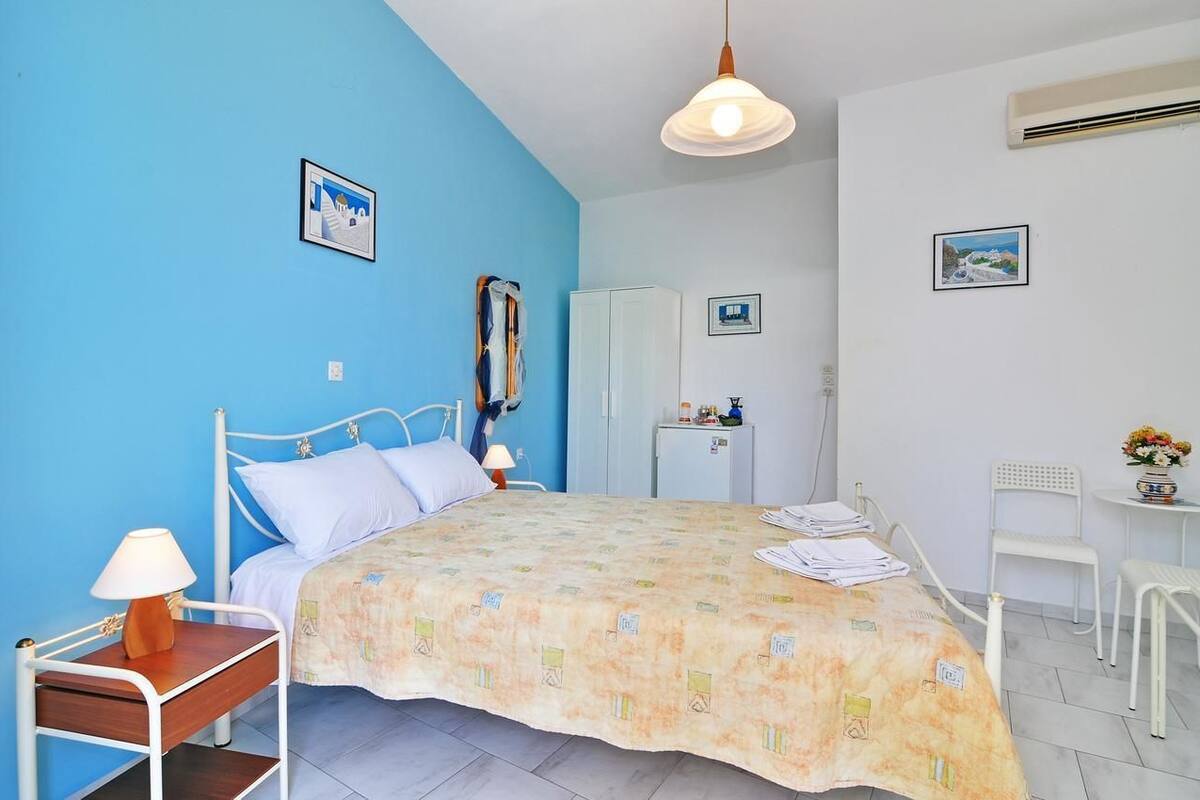 Quarto com cama, mesa de cabeceira, escrivaninha e cadeira.