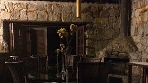 A stone-walled room with wicker furniture and a glass table. - Pousada Alpenhof (Sao Pedro de Alcantara)