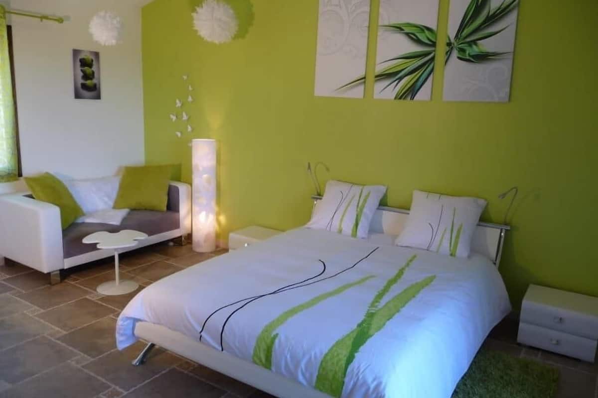 A bedroom with a bed, a sofa, a nightstand, and a floor lamp.