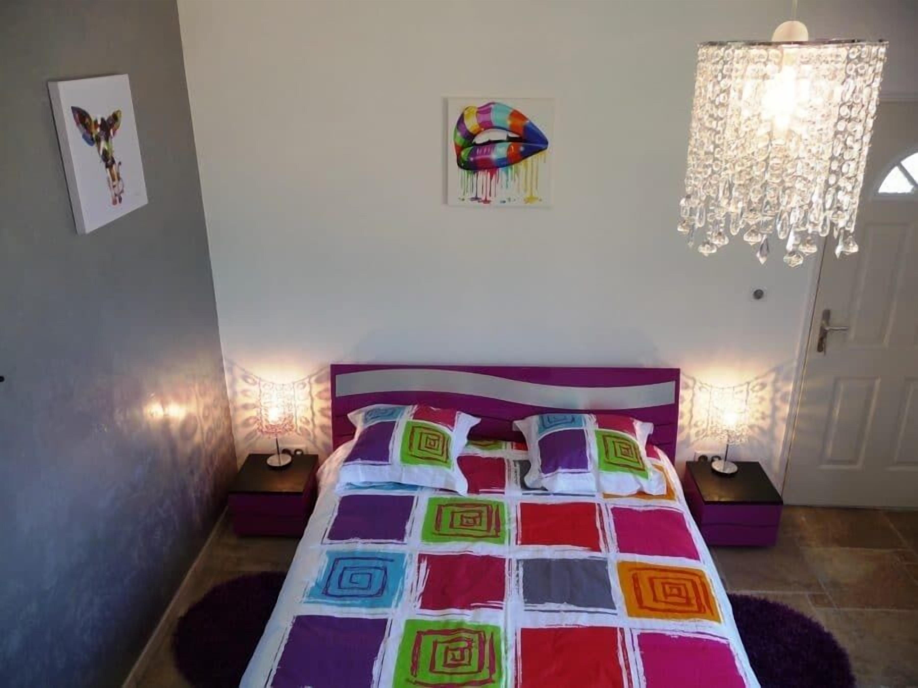 Een slaapkamer met een bed, twee nachtkastjes, een kroonluchter en wanddecoratie.